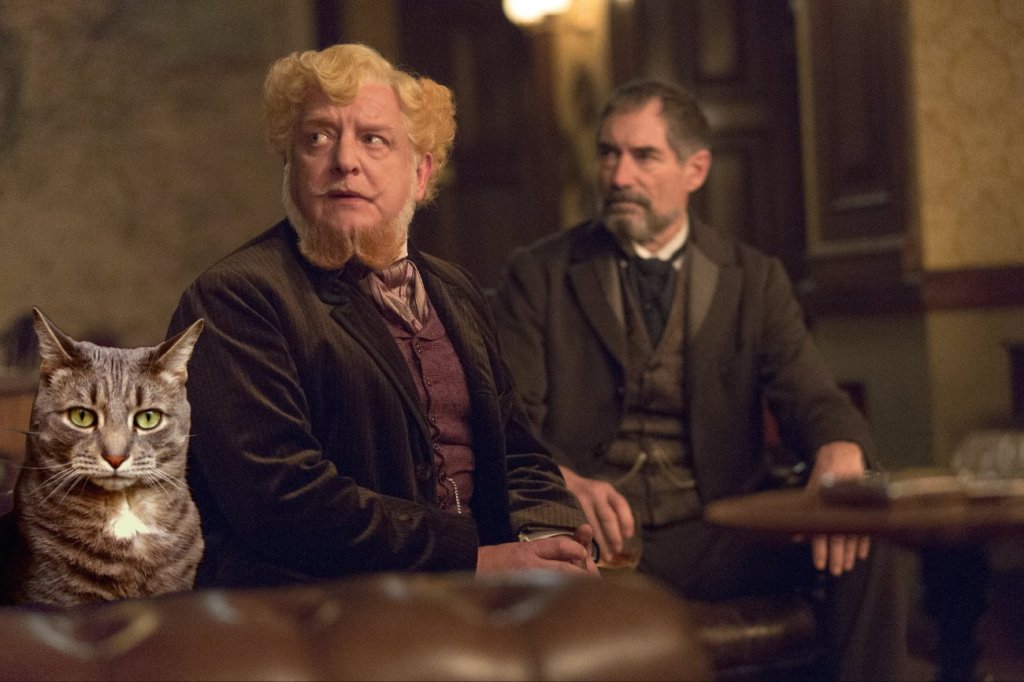 A scene featuring two men in period clothing sitting in a dimly lit bar, with a tabby cat prominently in the foreground.