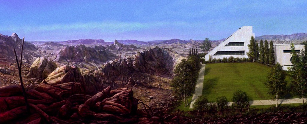 A futuristic white building set against a dramatic mountainous landscape, featuring sparse greenery and rocky terrain in the foreground.